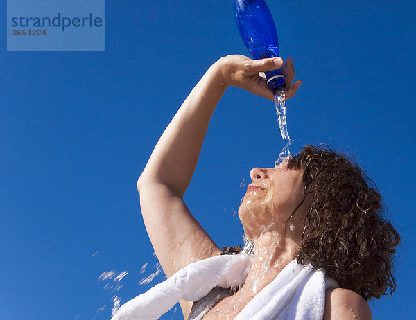 Frau gießt sich Wasser als Erfrischung über den Kopf