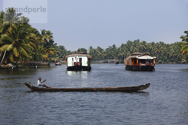 Mann in Langboot und Hausboote  Backwaters bei Alleppey  Alappuzha  Kerala  Südindien  Indien  Südasien  Asien