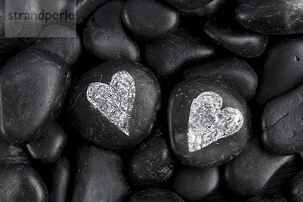 Zwei weiße Herzen auf schwarzen Steinen