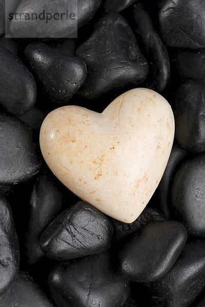 Weißes Herz auf schwarzen Steinen