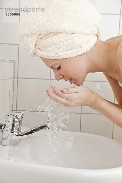Frau wäscht Gesicht mit Wasser