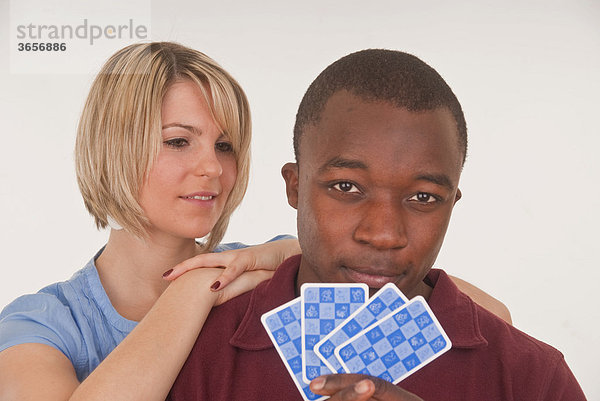 Farbiger junger Mann und junge Europäerin beim Kartenspielen