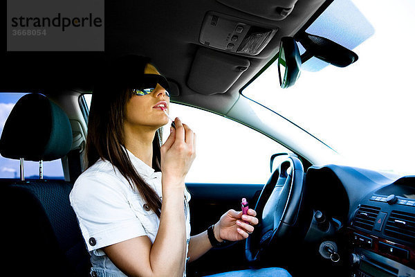 Junge Frau schminkt sich im Auto