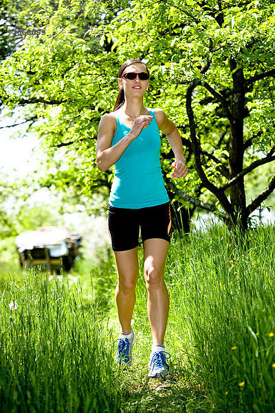 Junge Frau joggt durch Obstgarten