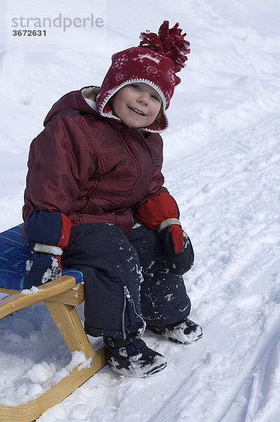 Kleiner Mädchen 2 Jahre mit Schlitten im Schnee
