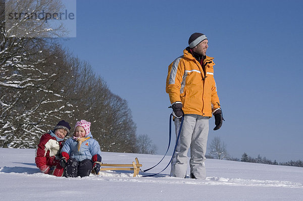 Familie im Winter beim Schlitten fahren