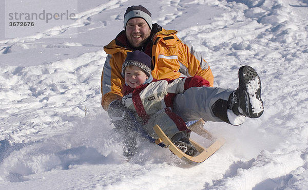 Familie im Winter beim Schlitten fahren