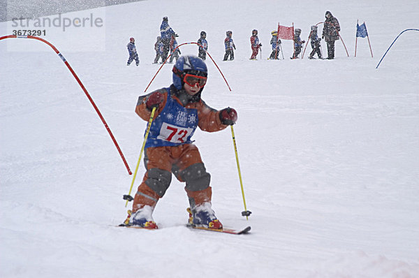 Kind beim Skifahren fährt durch Torbogen beim Abfahrtsrennen
