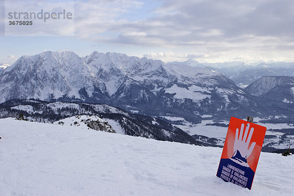 Lawinenwarnschild am Rand einer Piste im Schigebiet auf der Tauplitz im Hintergrund Grimmingmassiv Steiermark Österreich