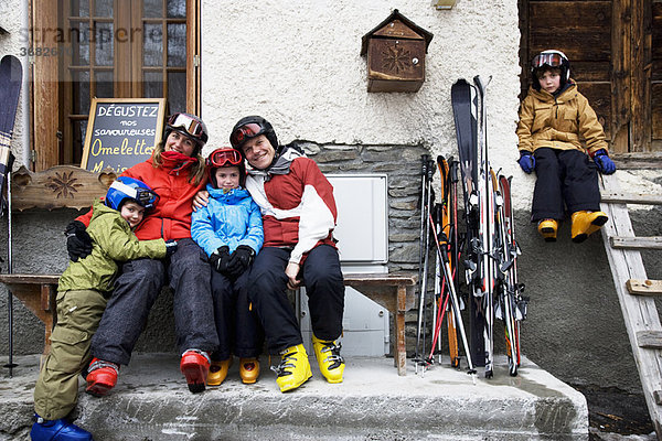 Familie sitzend vor der Scheune mit Skiern