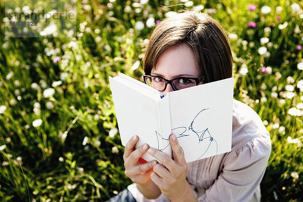 Frau versteckt sich hinter Buch