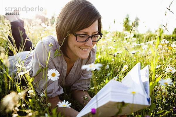 Frau liest Buch auf wilden Wiesen