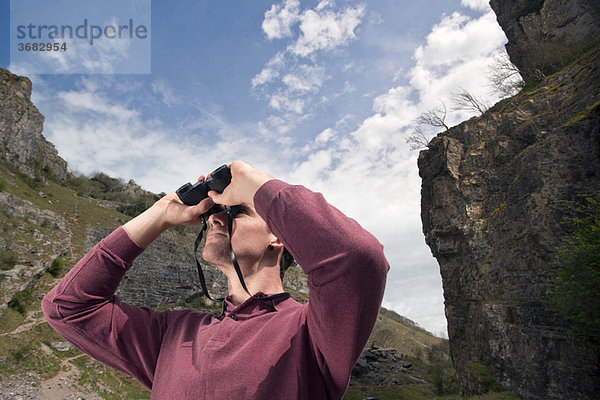 Mann im Tal mit Fernglas