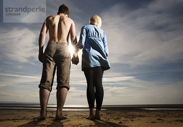 Paar hält sich am Strand an den Händen