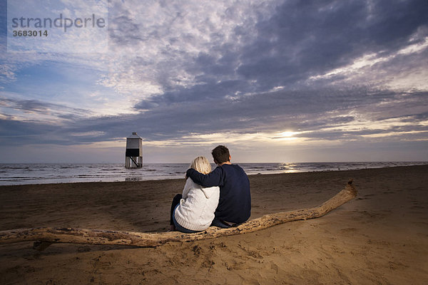 Paar beobachtet Sonnenuntergang am Strand