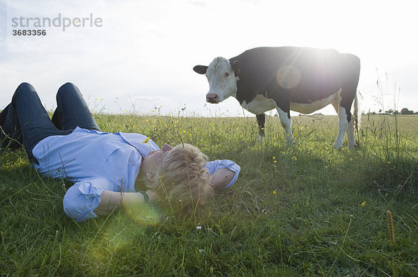 Frau entspannt im Feld mit Kuh