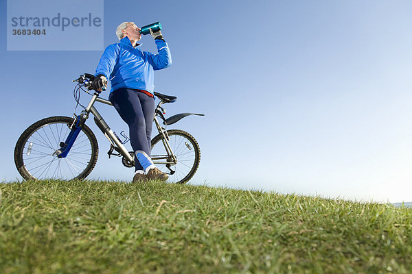 Älterer Mann trinkt Wasser auf der Fahrradtour