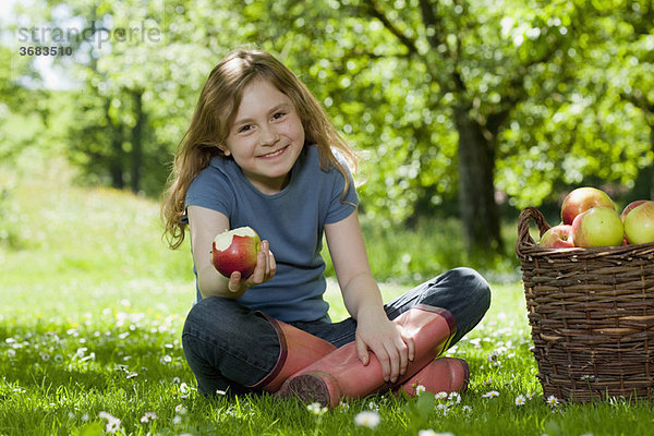 Mädchen auf der Wiese  das einen Apfel isst