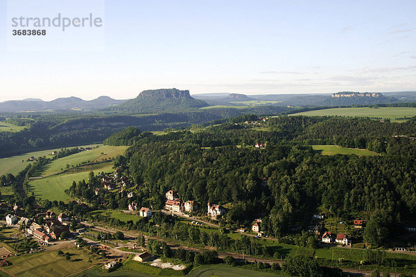 Deutschland  Sachsen  Elbsandsteingebirge  Sächsische Schweiz  Blick auf die Sandsteinformationen und ein Dorf bei aufgehender Sonne