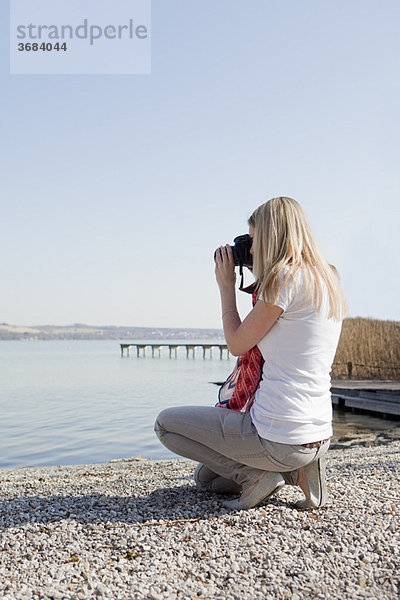 Frau beim Fotografieren am Meer