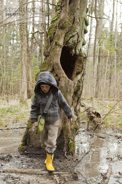 Junge  der im Wald durch den Schlamm schwappt.