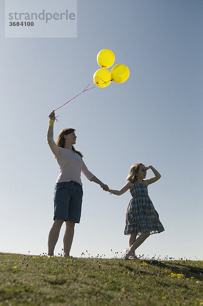 Frau und Kind mit Ballons auf dem Hügel