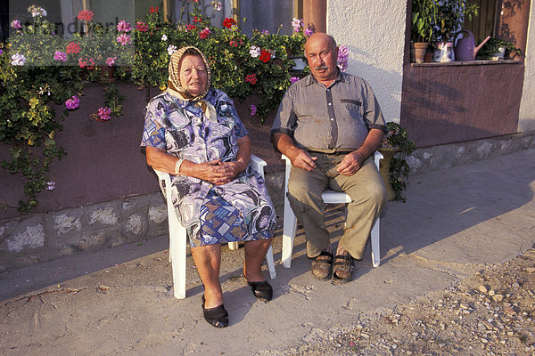 Altes ungarisches Paar sitzt auf Plastikstuehlen Eheleute Ungarn