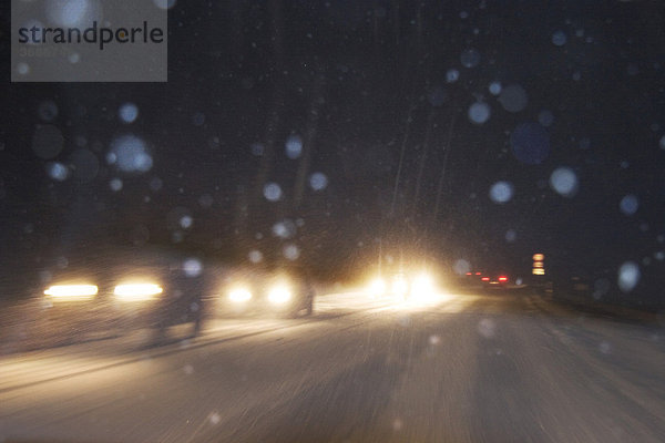 Straßenverkehr im Winter nachts bei Schneetreiben Landstraße Bayern Deutschland