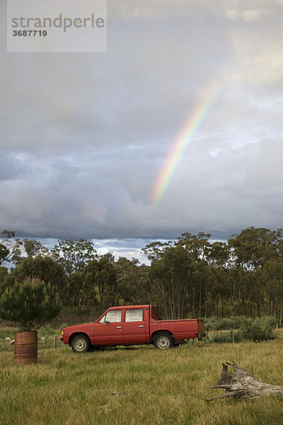 Ein Regenbogen am Himmel über einem Pick-up auf einem Feld