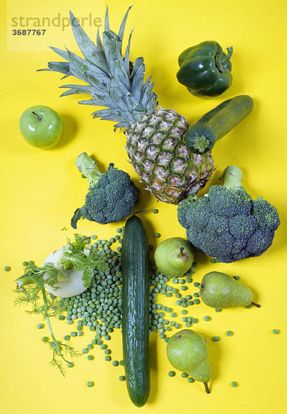 Anordnung von grünem Obst und Gemüse auf gelbem Grund