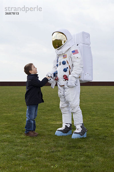 Ein Junge  der einem Astronauten die Hand schüttelt.