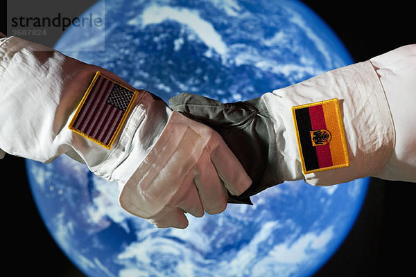 Ein amerikanischer Astronaut  der einem deutschen Astronauten die Hand schüttelt.