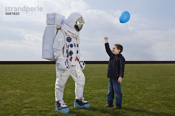 Ein Junge hält einem Astronauten einen Ballon entgegen.