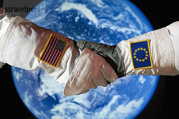 Ein amerikanischer Astronaut  der einem Astronauten aus der Europäischen Union die Hand schüttelt.