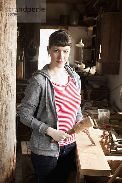 Eine Frau in einer Werkstatt mit Meißel und Schlägel