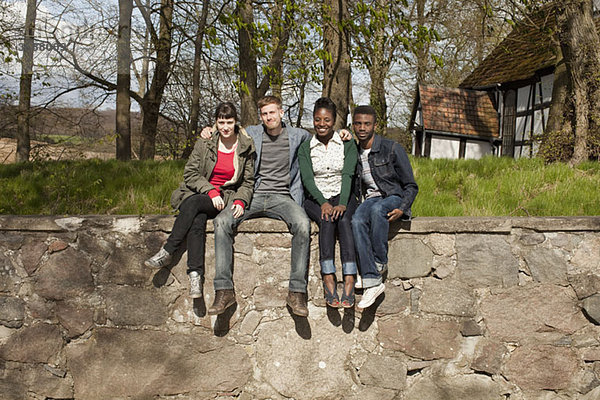 Vier Freunde auf einer Steinmauer sitzend