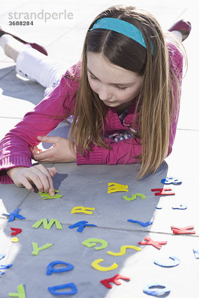 Ein Mädchen spielt mit Filzalphabetbuchstaben