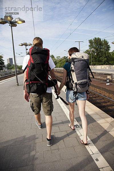 Ein Backpacker-Paar  das einen Bahnsteig hinuntergeht.