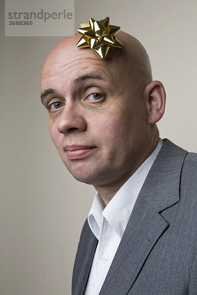 Porträt eines Mannes mit Geschenkbogen auf dem Kopf