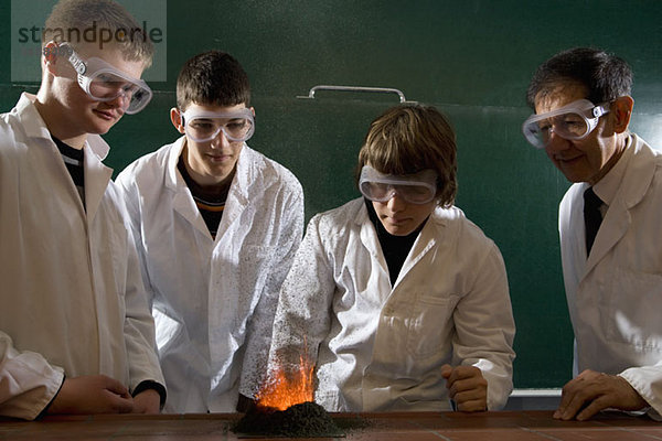 Ein Lehrer  der Schüler bei einem Chemie-Experiment mit angezündetem Schießpulver beaufsichtigt.