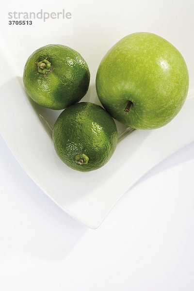 Grünes Obst  Limonen und ein Apfel auf Teller