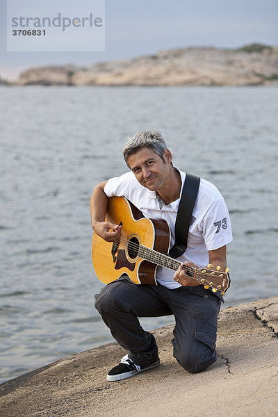Mann spielt Gitarre an der Schärenküste in Sotenäs  Schweden