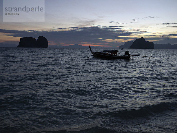 Longtailboot in der Morgendämmerung mit Blick auf eine Felsengruppe vor der Insel Ko Hai  Ko Ngai  Andamanensee  Provinz Satun  Südthailand  Thailand  Asien
