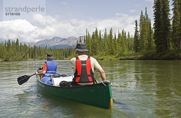 Paar  Mann und Frau  fahren Kanu  paddeln  oberer Liard River Fluss  dahinter die Pelly Mountains Berge  Yukon Territory  Kanada