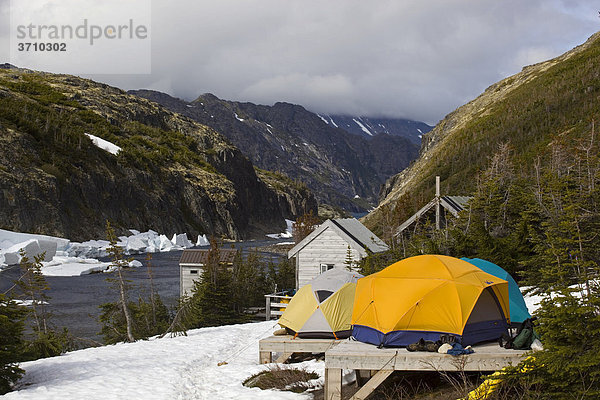 Historisches Happy Camp  Zelt auf hölzerner Plattform  Eisschmelze im Frühling  schmelzender Schnee  dahinter ein Fluß  Chilkoot Trail Wanderweg  Chilkoot Pass  Yukon Territory  British Columbia  BC  Kanada