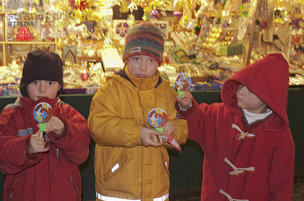 Drei Kinder vor einem Stand auf dem Christkindlmarkt Augsburg Deutschland