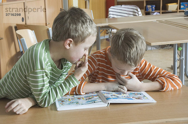 Schüler 2. und 4. Klasse Grundschule im Klassenzimmer beim Asterix Heft Lesen