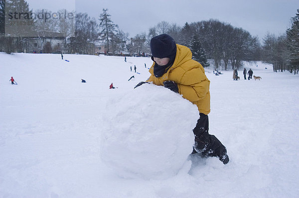 8-jähriger Junge rollt große Schneekugel