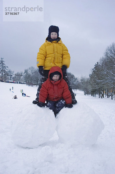 Zwei Jungen auf großen Schneekugeln