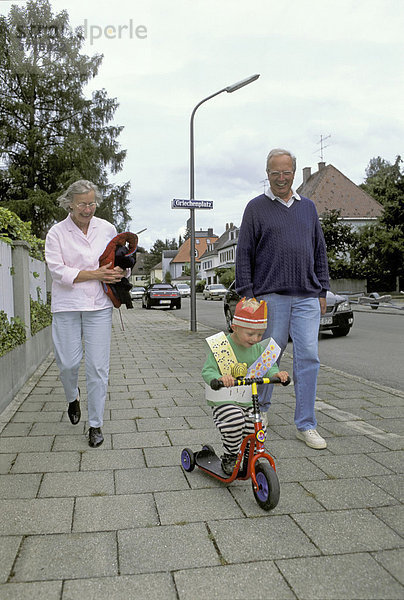 Großeltern gehen mit Enkel 2 Jahre mit dem Roller am Geburtstag spazieren